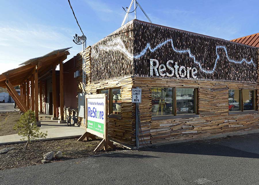 The side of the Restore an art-deco glass mosaic logo sits above salvages wood planks lining the storefront
